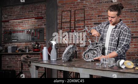 man work with the socket wrench, repair and cleaning engine parts on the workbench in home garage workshop, diy concept Stock Photo