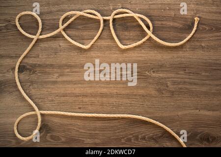 Two heart shapes on an old wooden wall made from knitted rope Stock Photo