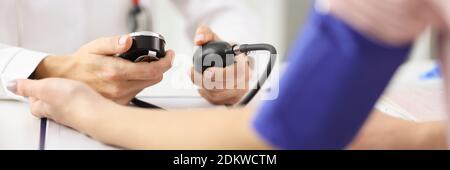 Doctor cardiologist measuring blood pressure of patient with tonometer in clinic Stock Photo
