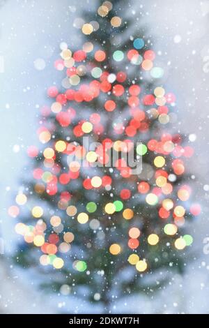 Blurred Christmas tree with colorful lights on white background with snowflakes around Stock Photo