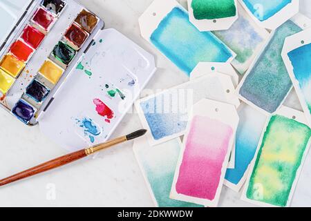 Homemade gift tags made out of watercolor paper and painted with watercolor paint in abstract free flowing designs. Stock Photo