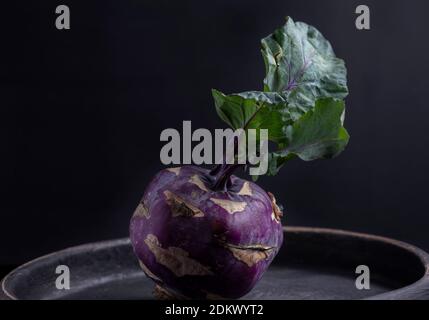 One purple kohlrabi on a black background Still life Dark food photography Stock Photo