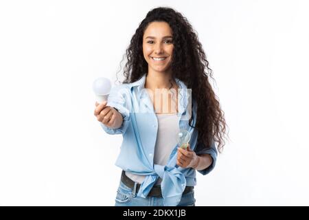 Smiling Lady Choosing Compact Fluorescent Lamp Lightbulb Standing, White Background Stock Photo
