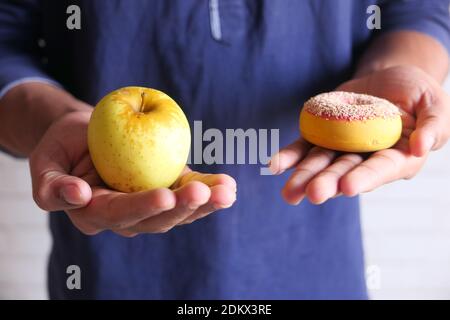 hand holding donuts and apple on hand close up  Stock Photo
