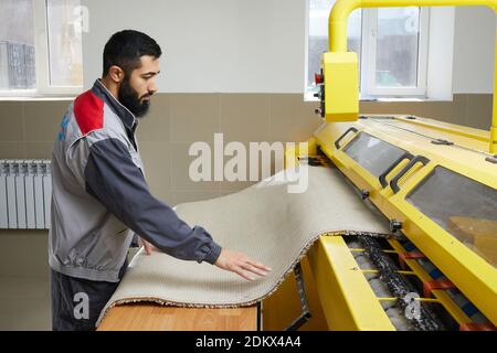 Man operating carpet automatic washing machine in professional laundry service Stock Photo