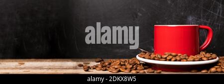 Red cup of coffee with coffee beans on dark textured background banner with copy space. Morning fresh energy concept. Stock Photo