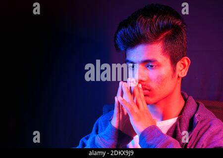 thoughtful young man sitting on chair at night  Stock Photo