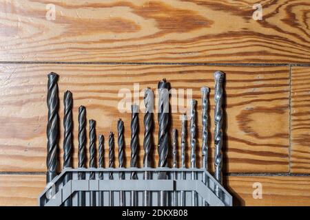 Detail of set of various drills in different sizes for wood, iron and concrete materials collocated together lying on wooden floor Stock Photo