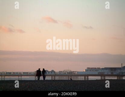 A couple walk along Brighton beach Stock Photo