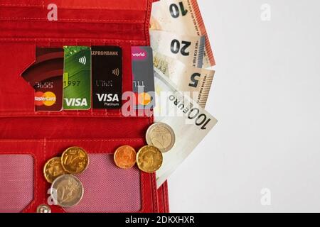 Open red wallet with credit and bank cards, bills and euro coins on a white background. . Stock Photo