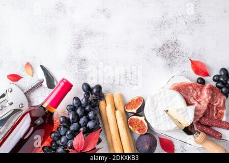 Appetizers on table with italian antipasto snacks and wine. Grape, figs, cheese camembert, bread stick, meat snaks. Antipasti, gourmet, romantic conce Stock Photo