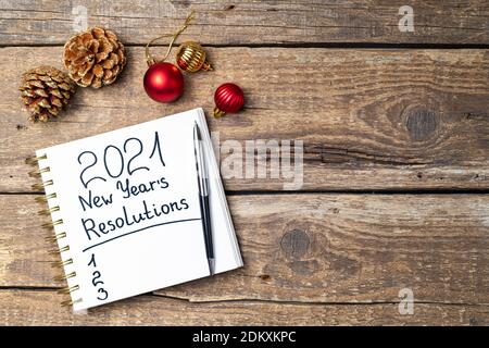 New year resolutions 2021 on desk. 2021 resolutions with open notebook, Christmas ornaments on wooden background. Goals, plan, strategy, action, idea Stock Photo