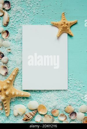 Summer template with greeting card. Little seashells, starfish and sea salt on a turquoise wooden background. Stock Photo