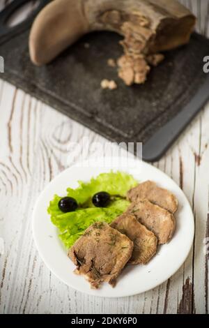 boiled beef tongue sliced in a plate on a wooden table Stock Photo