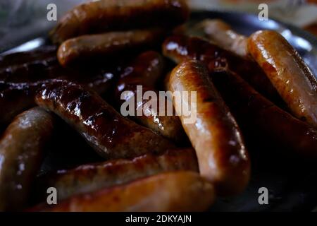 Grilled barbeque sausages on plate close up, meat meal at picnic Stock Photo