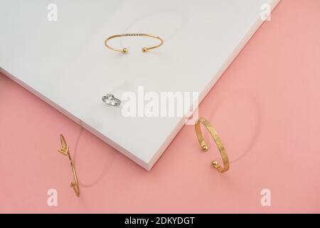 Flat lay of golden bracelets and ring on white and pink background Stock Photo