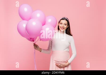 happy young pretty pregnant woman with balloons isolated on pink Stock Photo