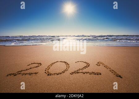 Happy New Year 2021 concept, lettering on the beach. Written text on the sea beach at sunrise. Stock Photo