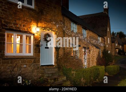 UK, England, Oxfordshire, Banbury, Wroxton, cottages around village green illuminated for Christmas Stock Photo