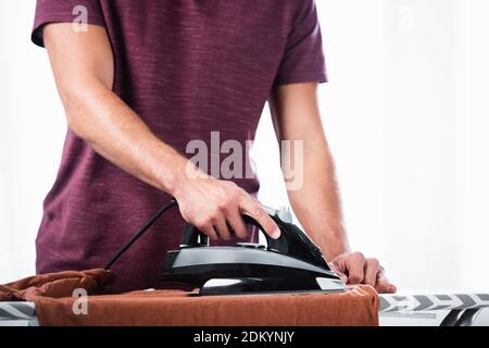 Cropped view of young man ironing clothes on board at home Stock Photo
