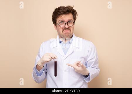 Doctor scientific research assistant in a medical coat holding tube with liquid. Studio shot Stock Photo