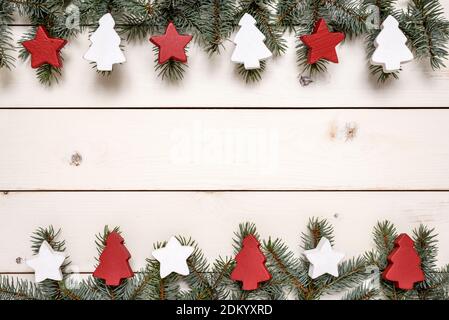 Christmas frame made of fir branches and wooden Christmas ornaments on white table with copy space for text. Christmas and New Year concept. Stock Photo