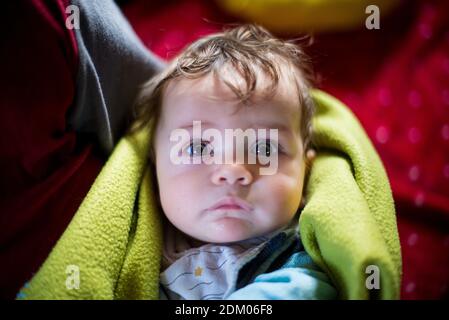 portrait of 5 month old baby wrapped in blanket in mother's arms Stock Photo