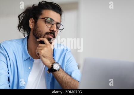 Closeup Portrait Of Focused Handsome Arab Guy In Eyeglasses Working On Laptop Stock Photo