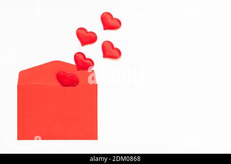 Opened red envelope and many hearts on a white background with copy space. Stock Photo