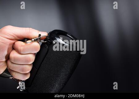 Black wireless portable speaker in hand, on black background with copyspace. Stock Photo