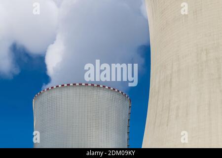 Detail of nuclear power plant cooling towers from concrete and white steam on blue sky background. Water evaporation in generating station. Ecology. Stock Photo