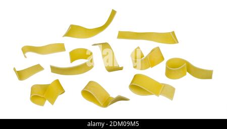 Set of separated raw wide pasta noodles isolated on white background. Closeup of flat ribbon tagliatelles group. Dry solid strips of wheat flour dough. Stock Photo
