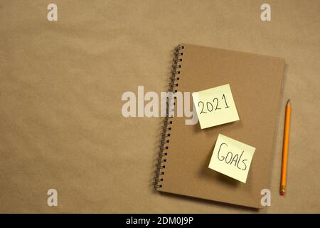 Notebook with yellow sticky notes with 2021 and goals for New Year on brown paper background with classic pencil, business or school, education Stock Photo