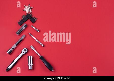 Creative christmas tree on red background, made of wrenches.Set of tools supplies for repair car on xmas backdrop. Industrial greeting card Stock Photo