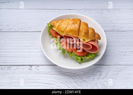 Fresh croissant sandwich with ham , cheese , tomato and salad leaf on white wooden background. French breakfast. Tasty croissants with copy space Stock Photo