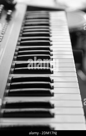 Keyboard of music electronic synthesizer, piano on blurred background. Shallow focus. Black and white image. Stock Photo