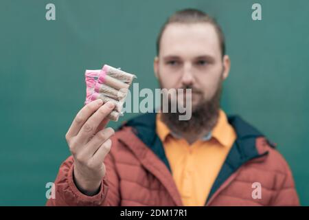 Serious Young Man Holding Firecrackers in his Hand. Bearded Guy Getting Ready for New Year Fun Stock Photo