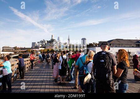 Passengers waiting for the San Francisco to Oakland ferry queue on Pier 41 in the sun. San Francisco, California United States of America Stock Photo