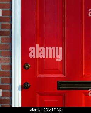 Bright red paneled front door detail with knob, lock and mail slot Stock Photo