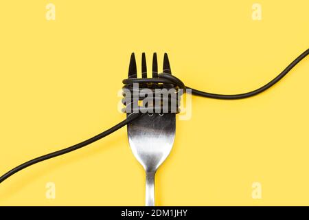 A black cable rolled in a fork on a yellow background Stock Photo