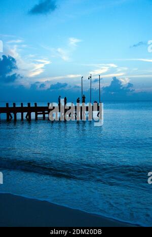 Couples walk on a pier at sunset, Cozumel, Mexico. Stock Photo