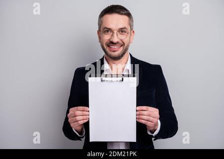 Close-up portrait of his he nice attractive cheerful cheery mature man holding in hand empty blank copy space clipboard recommending service isolated Stock Photo