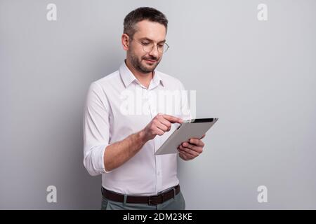 Portrait of his he nice attractive intellectual mature man holding in hands ebook analyzing searching information e-banking isolated over light gray Stock Photo