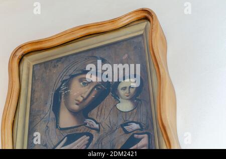 Ukraine, Nikolaev - August 26, 2020: ancient icon of the mother of God with the baby Jesus in her arms. The icon in a massive oak frame hangs on the w Stock Photo