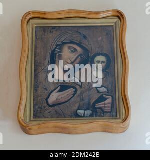 Ukraine, Nikolaev - August 26, 2020: ancient icon of the mother of God with the baby Jesus in her arms. The icon in a massive oak frame hangs on the w Stock Photo