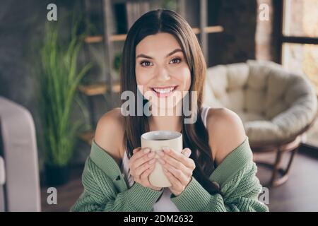 Photo of optimistic brunette cute girl from home hold cup wear green shirt indoors Stock Photo