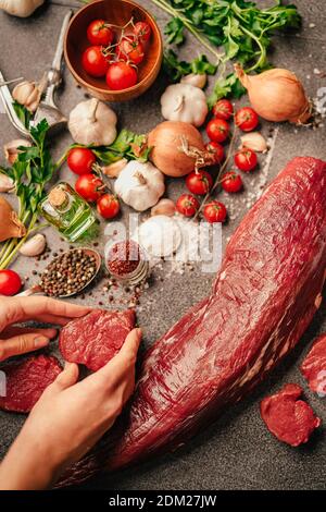 Fresh meat preparation and portioning.Whole uncut beef tenderloin.Raw meat seasoning.Hands portioning filet mignon steaks. Grass-fed beef steak from t Stock Photo