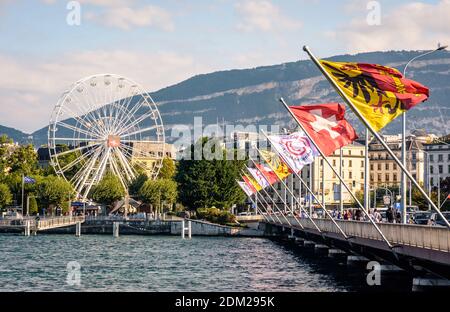 Flags of Geneva and Swiss flags flying on the Mont Blanc bridge on the Lake Geneva with the ferris wheel in the distance. Stock Photo