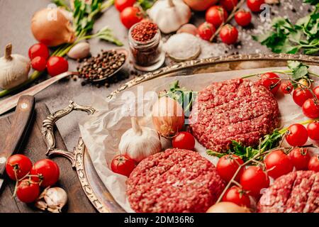 Round ground beef portioned beef patties made from beef mince prepared for on a platter.Hamburger meat seasoned and ready for a barbecue.Spices and co Stock Photo