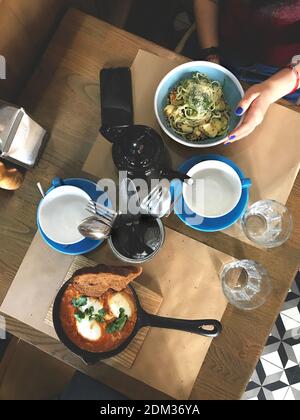 Cozy dinner at cafe with a friend. Top view of two plates with zuccini spagetti and shakshuka Stock Photo
